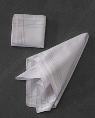 Folded beige handkerchiefs arranged on a dark background, showcasing classic men's accessories in a...