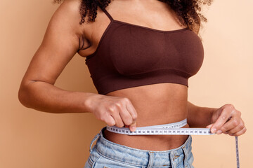 Young woman measuring her waist with a tape measure showcasing a healthy and fit lifestyle on a...