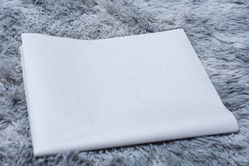 Minimalistic newspaper mockup with blank folded paper lying on a fluffy gray carpet. Layout for...