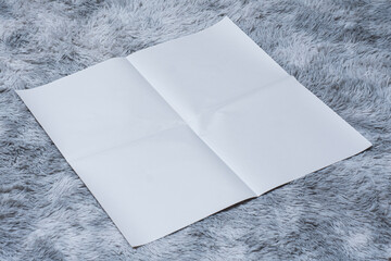 Minimalistic newspaper mockup with blank folded paper lying on a fluffy gray carpet. Layout for...