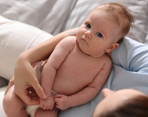 Mother putting her cute newborn baby to sleep on bed at home, above view