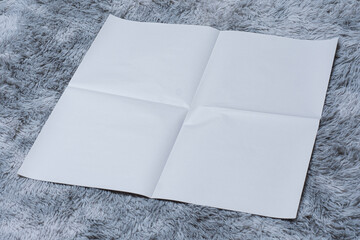 Minimalistic newspaper mockup with blank folded paper lying on a fluffy gray carpet. Layout for...