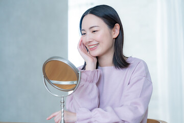 部屋で鏡を見る女性