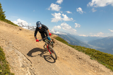 Man biking downhill in the Alps on rugged terrain