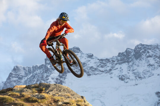 Man biking downhill in the Alps with snow-capped peaks