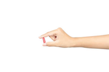 Close-up of a female hand holding a single red medicine capsule or pill for healthcare treatment and wellness, isolated on white background with clipping path.