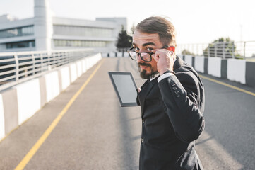 Businessman with Glasses and Tablet Focus, Technology, Urban Setting