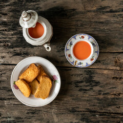 Traditional Indian Tea Time with Rusks and Pink Chai on Rustic Wooden Background