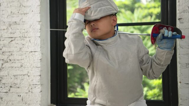 Before the tournament day, a boy dressed in fencing gear are rehearsing in gym