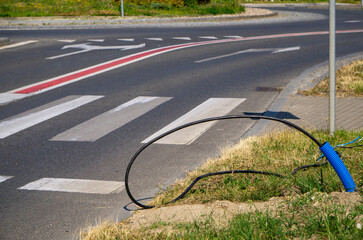 black cable protruding onto the roadway near a pedestrian crossing at an intersection, indicating...