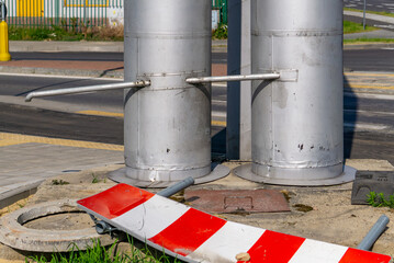 two vertical district heating pipes with metal support brackets, a fallen red-and-white warning...