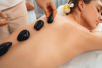 Hot stone massage at spa salon in luxury resort with day light serenity ambient, blissful couple...