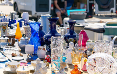 Colorful glassware, porcelain, and ceramics displayed for sale at a flea market or outdoor bazaar...