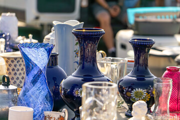 colorful glass vases and vintage glassware displayed on a table at an outdoor flea market.