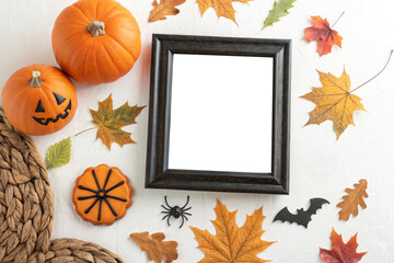 Halloween arrangement with pumpkins frame autumn leaves spider bat and pumpkin cookie on white surface