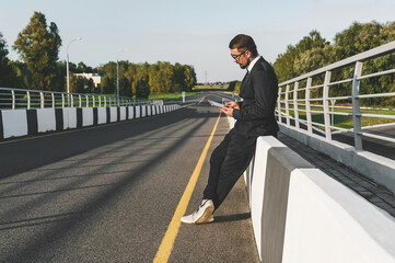 Businessman Leaning on Barrier Using Tablet Roadside Technology