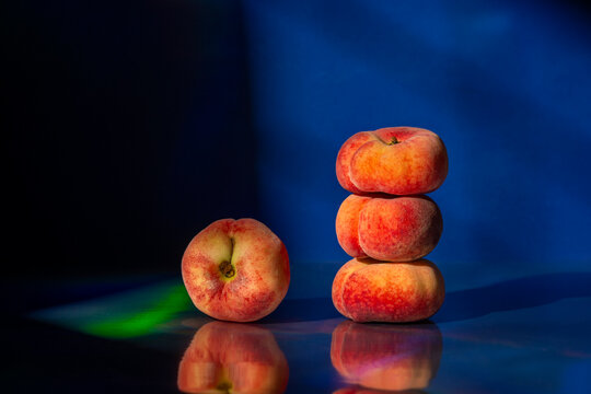 Stack of flat peaches on dark reflective surface
