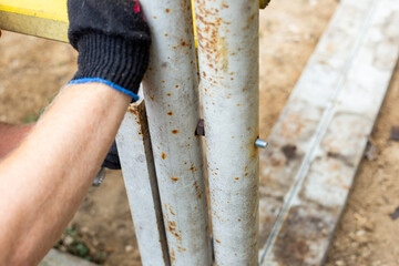 Close-up of a gloved hand securing a metal structure with a bolt, during the construction of a...
