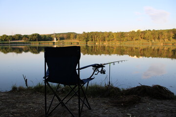 A tranquil fishing scene by a calm lake at sunset.
