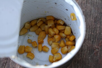 Open tin can with scattered yellow corn kernels inside.