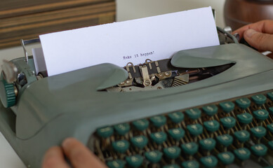Close-up of a vintage typewriter with the phrase make it happen typed on a sheet of paper,...
