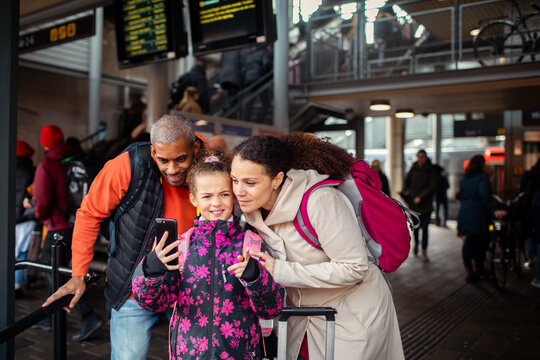 Family looking for directions on smartphone at busy train station before travel