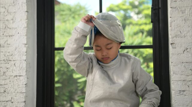 Before the tournament day, a boy dressed in fencing gear are rehearsing in gym
