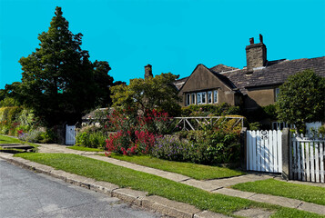 “Charming cottages and vivid gardens line a narrow lane beneath a vibrant blue sky. Tall trees...