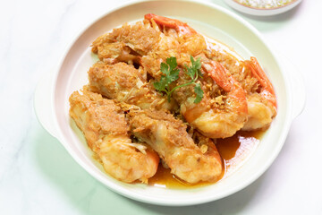 Deliciously fried shrimp served on a white plate, garnished with herbs and complemented by a flavorful sauce.
