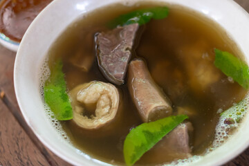 A steaming bowl of savory soup with tender meat and fresh herbs, representing traditional culinary...
