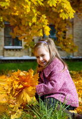 Little girl holding yellow autumn leaves, smiling outdoor park. Seasonal joy child happiness concept