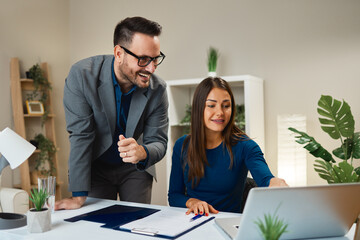 Businesspeople working together in office using laptop and smiling