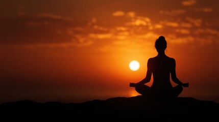 Woman meditating in serene lotus pose against vibrant orange sunset sky backdrop