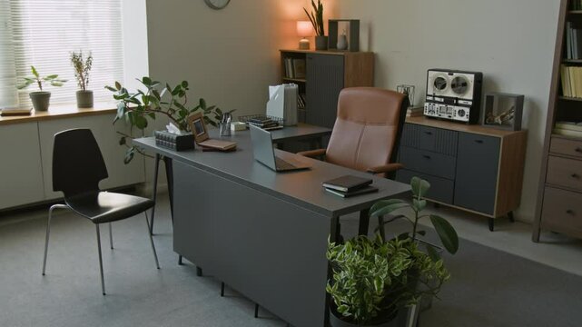 Background shot of psychotherapists desk with laptop and box of tissues in cozy room of private therapy practice decorated with green plants and modern furniture, copy space