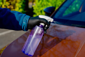 Naklejka premium Applying liquid ceramic coating to vibrant orange car panel to protect it from scratches, chips and ultraviolet damage. Applying nano coating for long lasting car paintwork