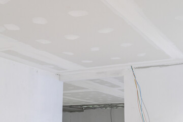 Gypsum board ceiling in building interior undergoing renovation. Smooth plastering on edges, with...
