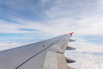 View from the airplane window at a beautiful cloudy sky and the airplane wing