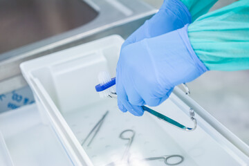 Close-up of gloved hands meticulously scrubbing medical tools in a disinfectant solution,...