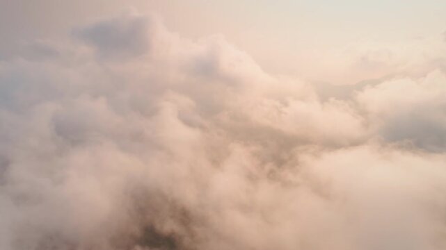 Capturing a breathtaking aerial view of fluffy cloudscapes during sunset, creating a serene atmosphere filled with warm pastel colors that evoke tranquility and beauty