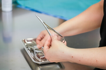 Detailed view of a person's hands preparing sterile surgical instruments, like forceps, from a...