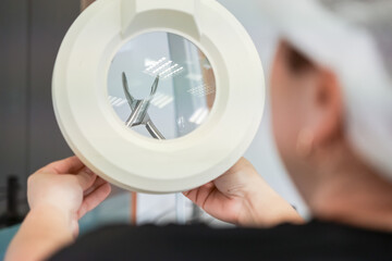 Professional meticulously inspects a medical instrument through magnifying lamp, ensuring precision and stringent quality control for healthcare device production
