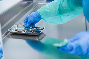 A healthcare professional prepares sterile surgical instruments on a stainless steel tray with...