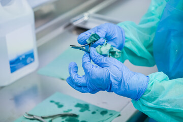 Close-up of a healthcare worker's gloved hands meticulously sterilizing medical instruments with a...