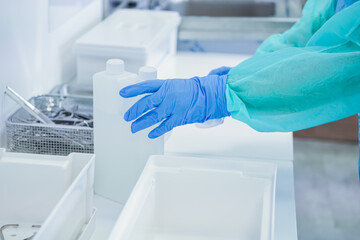 Close-up of medical worker's gloved hand and protective sleeve, handling disinfectant solution...
