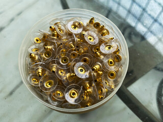 The objects in the image are golden bullet clutch earring backs, designed with clear silicone pads...