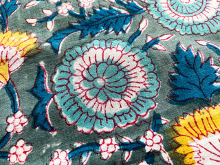 The close-up captures a detailed Mughal floral pattern in deep blue, meticulously block printed on...