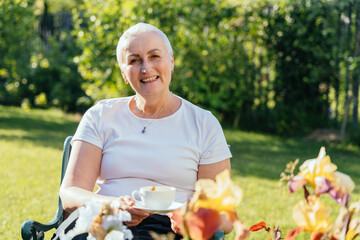 Smiling elderly woman holding cup and enjoying morning in garden