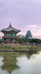 Obraz premium Seoul, South Korea - April 9, 2025: Hyangwonjeong Pavilion at Gyeongbokgung Palace reflected in the calm pond under a cloudy sky, highlighting traditional Korean architecture.
