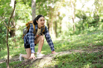 Active Hiking. Young woman climbing a rocky path in a lush forest.