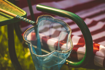 Blue butterfly net hanging from a green and red striped garden swing captures the essence of summer...